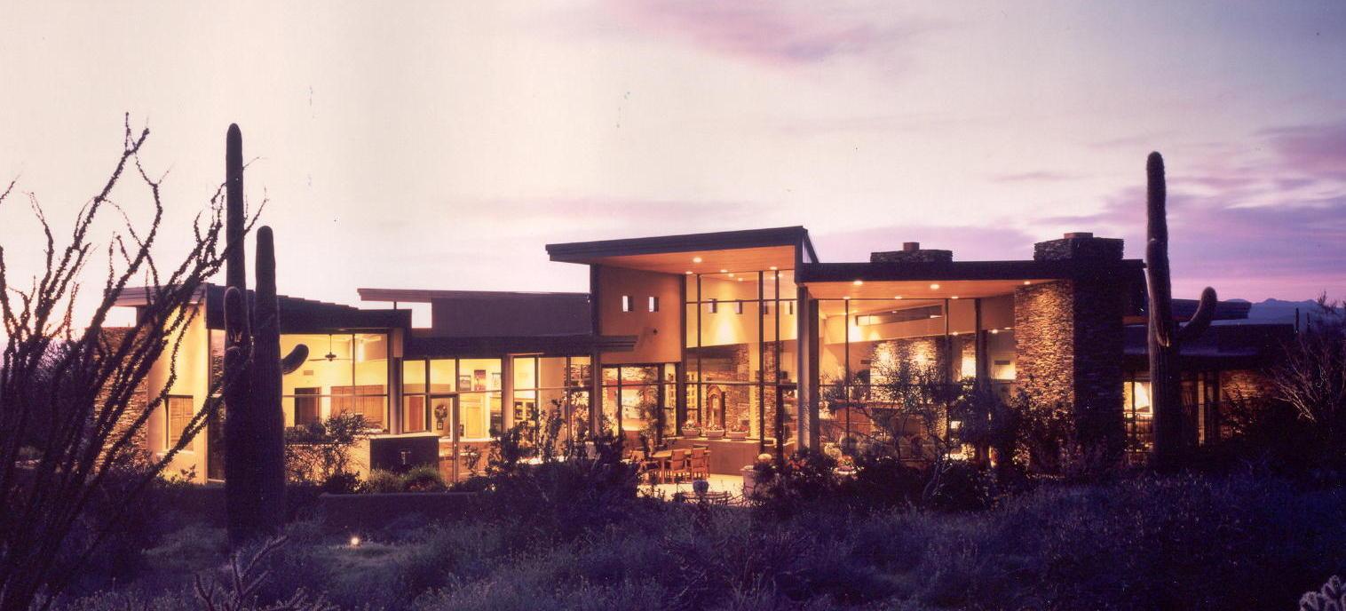 Modern desert residence with cantilevered rooflines glowing at dusk