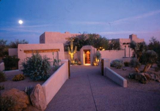 Adobe residence with lighted walkway at twilight